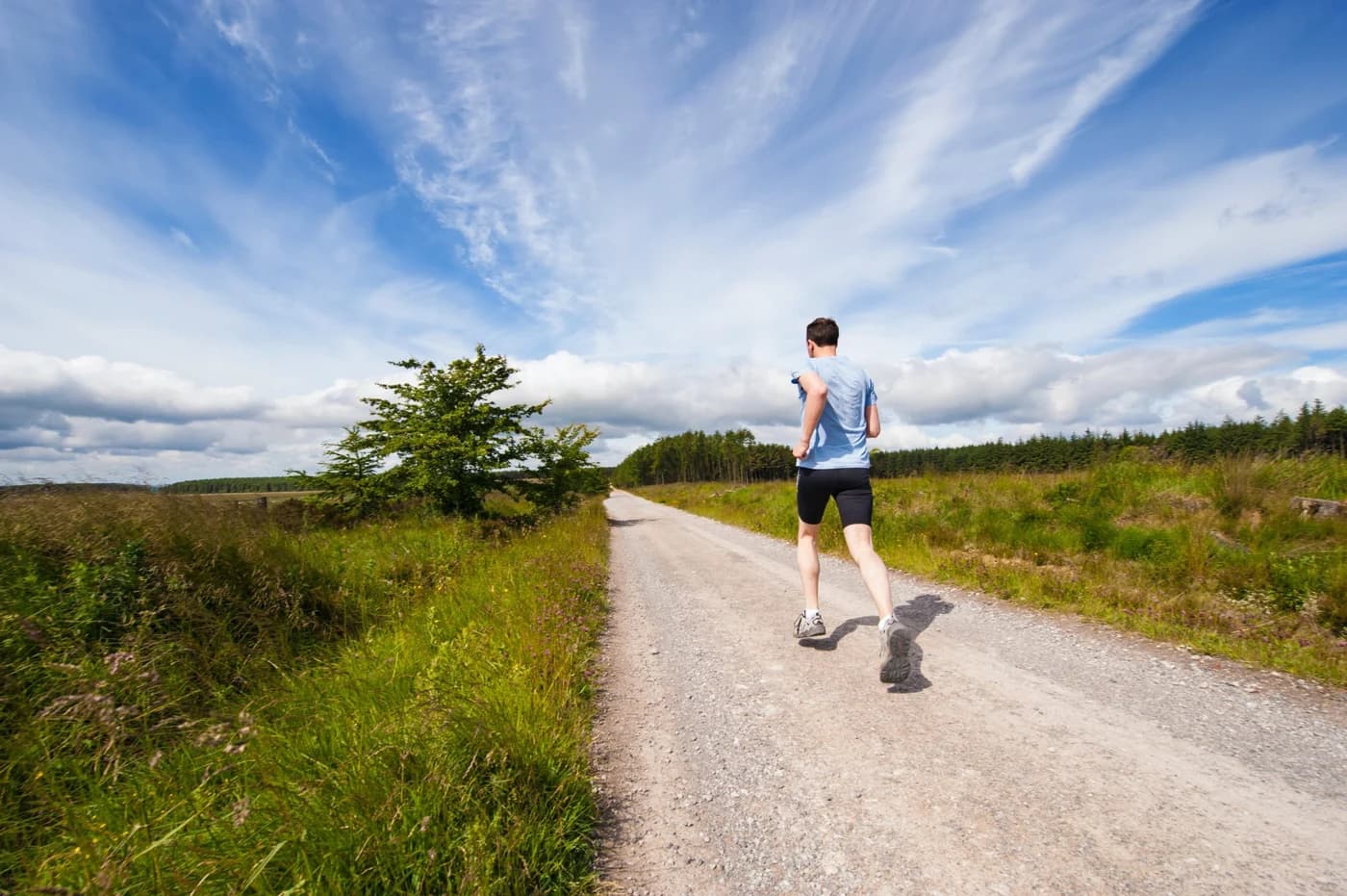 An adult man running on a countryside road